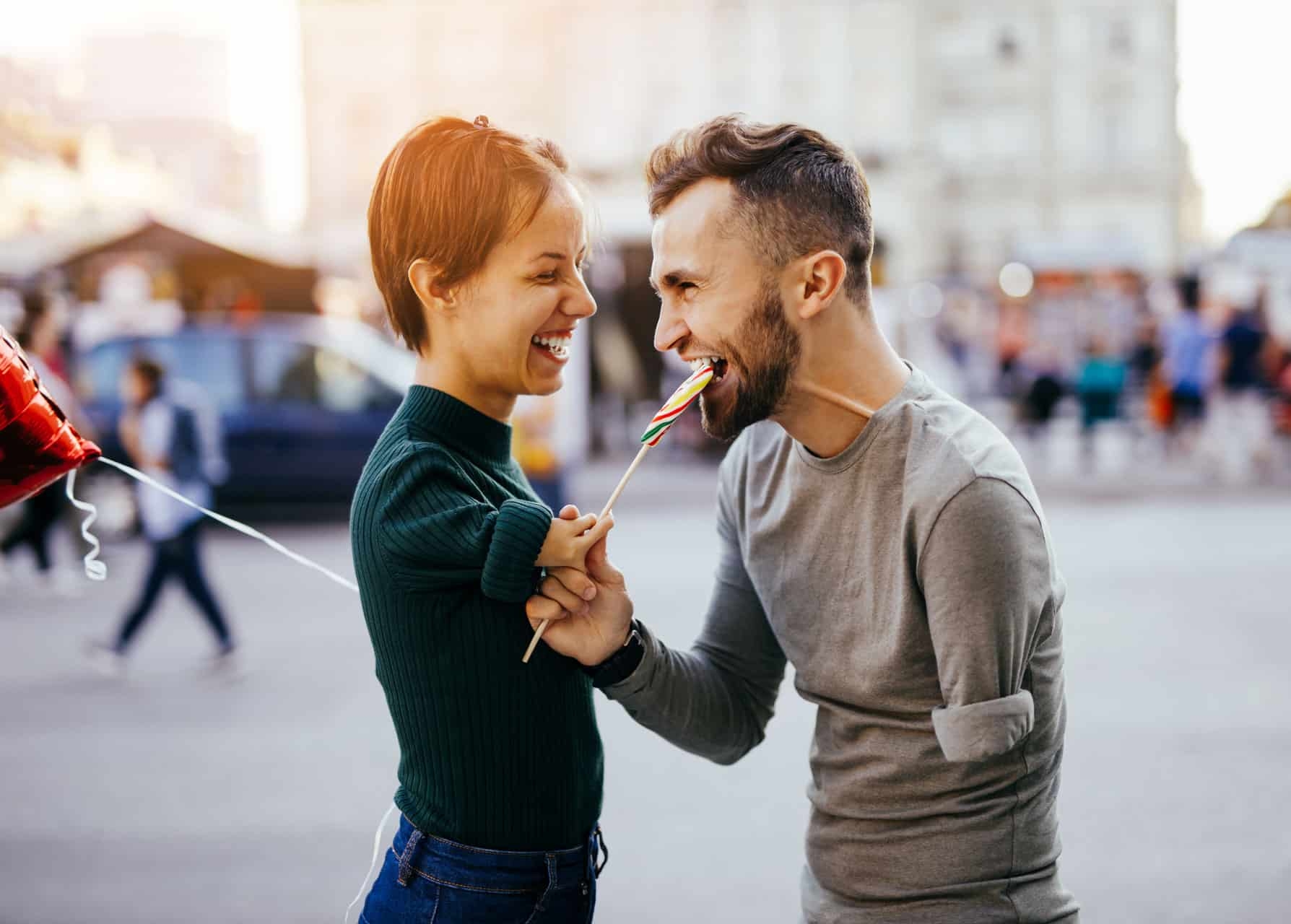 Romantische Liebesbeziehung von junger Frau mit Behinderung und ihrem Partner mit Behinderung. sie hält großen Lollipop in Hand und lässt ihn abbeißen